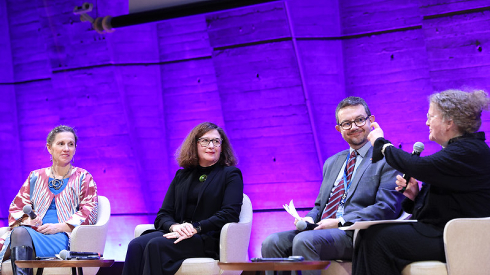 Amanda Watkins speaking on stage, alongside three other panelists