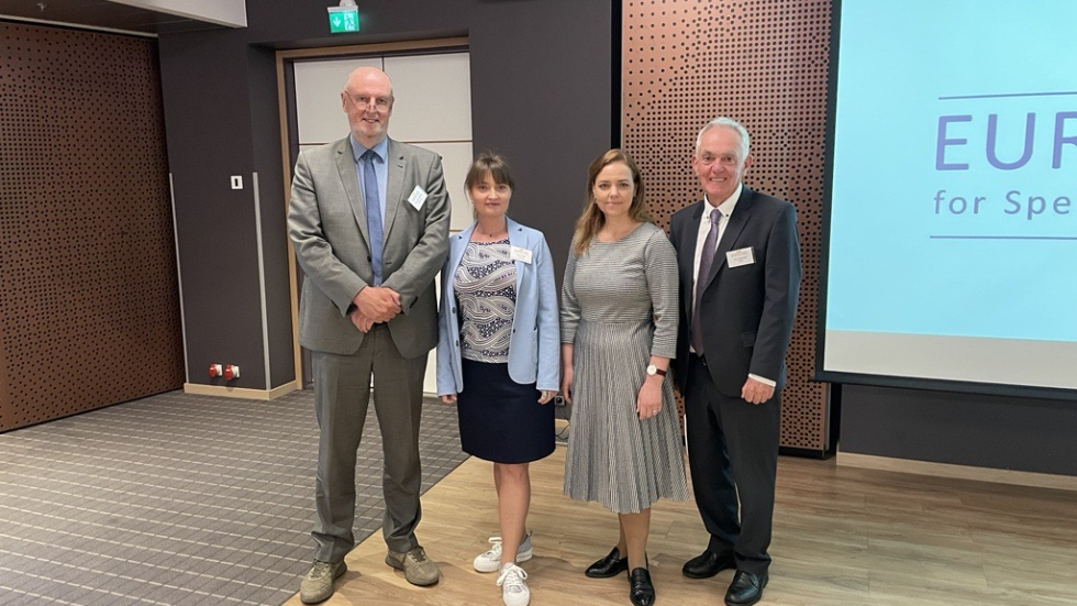 Four people standing in front of a presentation screen