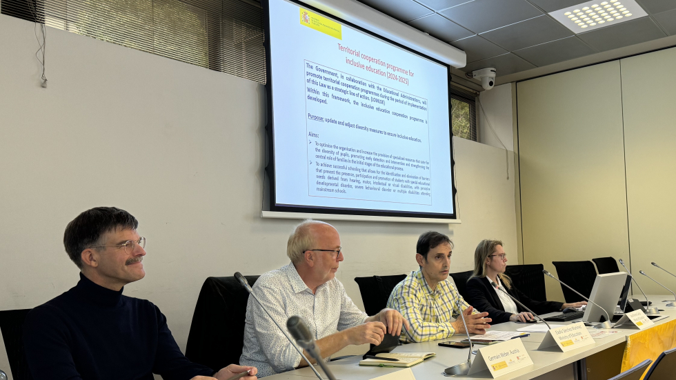 Four people sit in front of a presentation screen