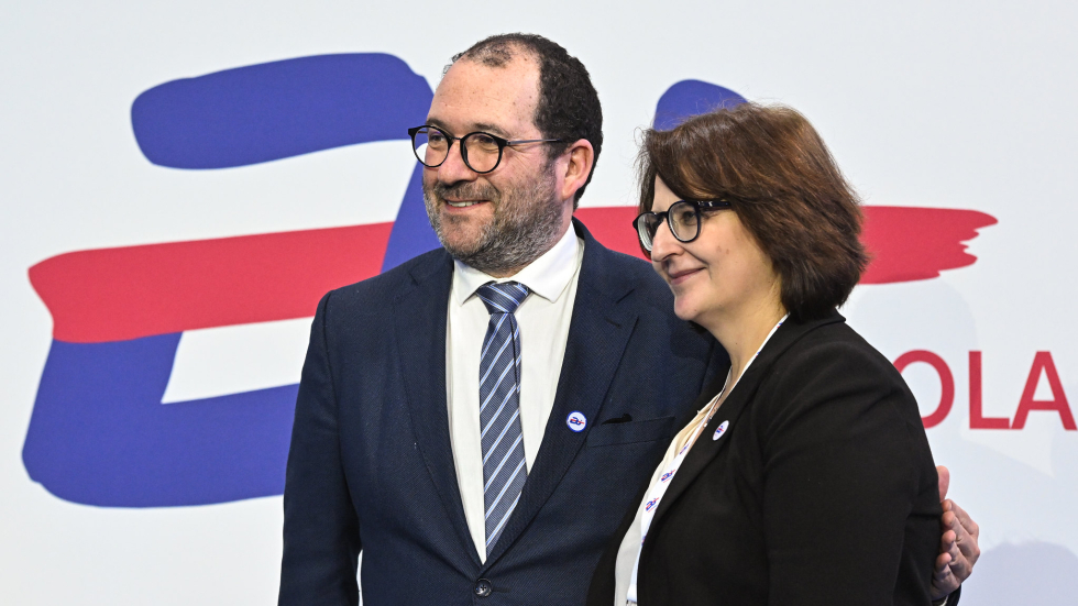 João Costa and Elżbieta Neroj standing side-by-side, smiling to the side of the camera