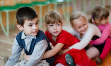 Four children sitting on the floor with their arms linked around each other