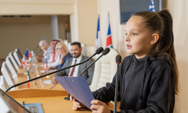 A girl speaks into a microphone at a conference