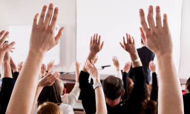 Learners in a classroom with their hands in the air