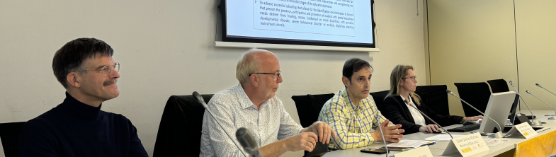 Four people sit in front of a presentation screen