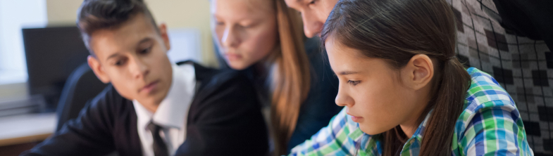 Children working at a computer with their teacher