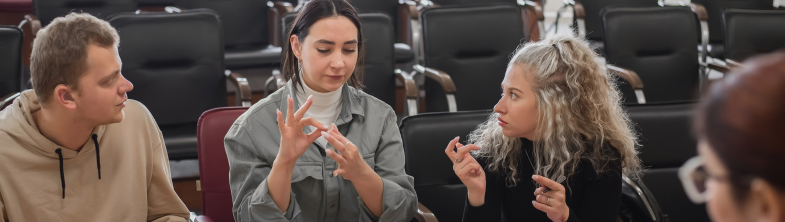 Three young people use sign language to present information to their teacher