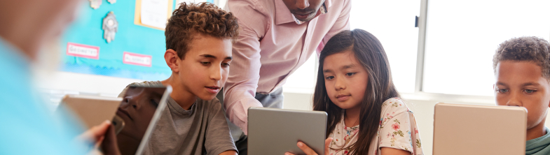 A teacher and two learners look at a tablet screen