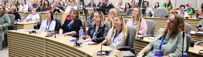 Participants in the conference sitting at desks in rows in a conference room