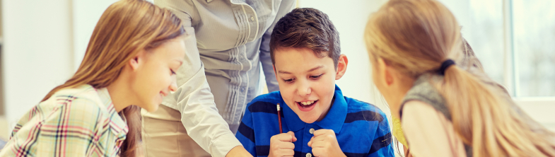 A teacher congratulates a boy on his work as his friends watch