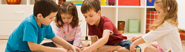 Four children playing with wooden building blocks