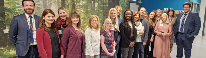 A group of people stand in front of wall with a picture of a forest of trees on it