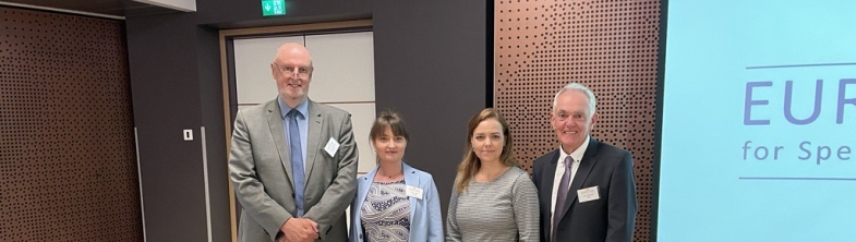 Four people standing in front of a presentation screen