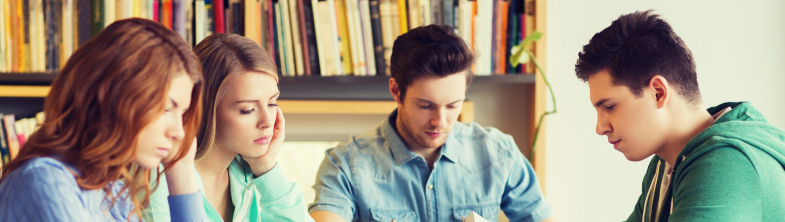 four young people reading at a table