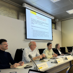 Four people sit in front of a presentation screen