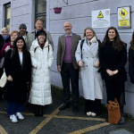 A group of people stand outside a school building