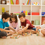 Four children play with building blocks that have numbers and letters on them